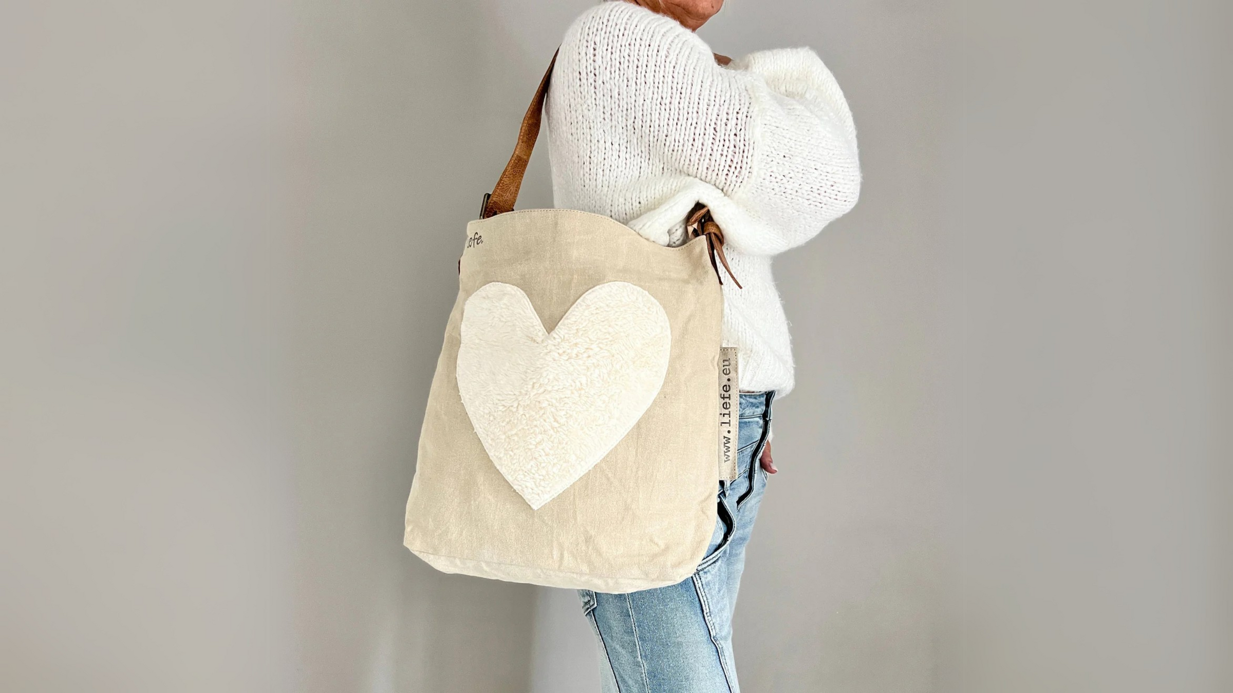 Naturfarbene Country-Tasche mit Herz aus Teddy-Stoff, getragen über der Schulter.