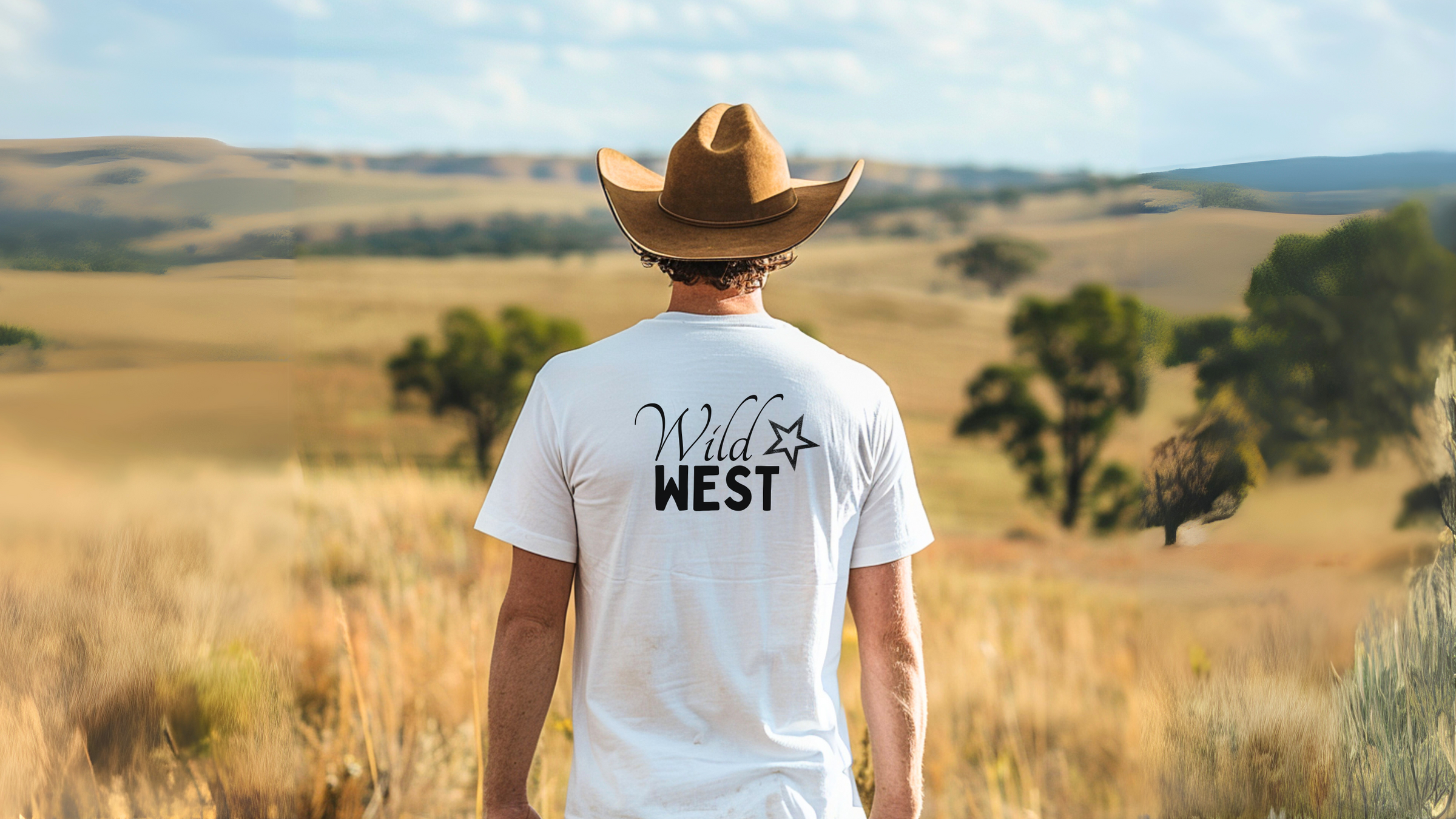Mann mit Cowboyhut und weissem WILD WEST Shirt stehend in einer weiten Präri